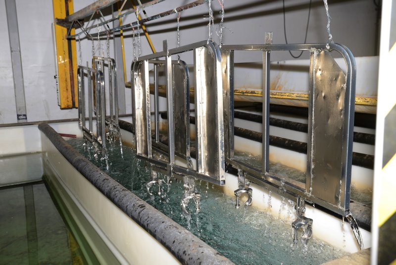 A set of zinc-plated steel gates for an abbatoir receive their final rinse in the electroplating process.
